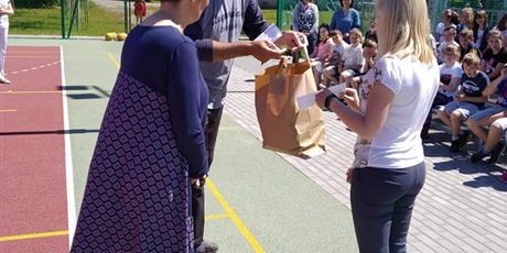 Powiększ grafikę: Nauczyciel wychowania fizycznego przekazuje na ręce wychowawcy klasy 0 nagrody na Rowerowy maj.